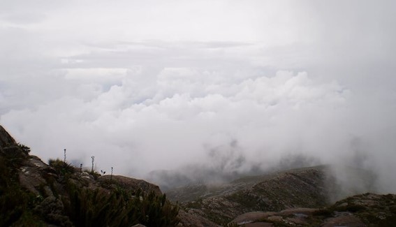 Mostra muitas nuvens vistas de cima de uma montanha