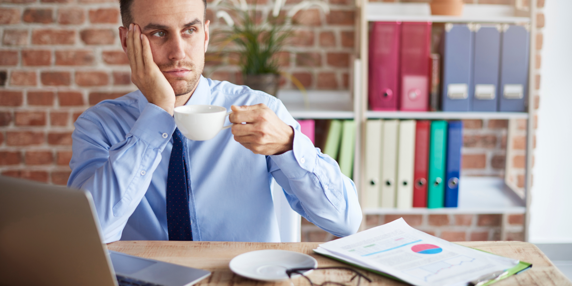 Homem de gravata sentado e tomando café